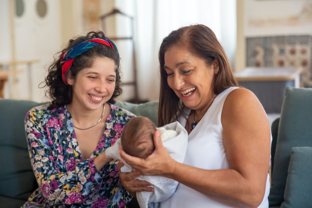 A mother passing her infant to a woman who looks like her mother
