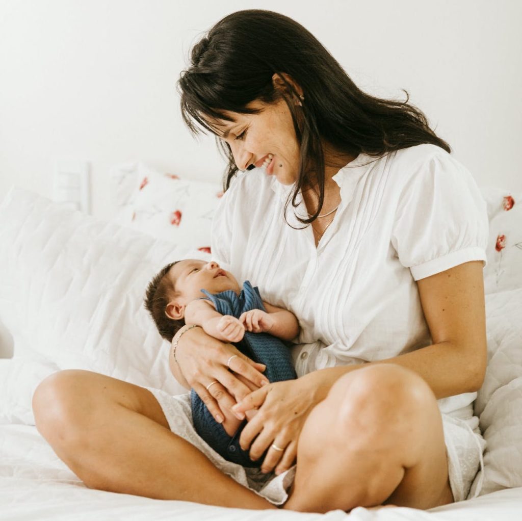 A mother smiling down at her baby laying cradled in her lap